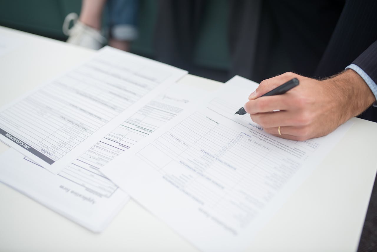 Close-up of a hand signing insurance documents in an office setting.